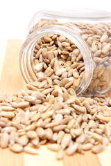 Heap of sunflower seeds in glass jar on wooden cutting board