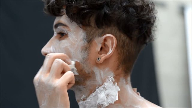 Young male actor or performer applying zombie make-up on his fac