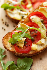 Grilled country bread with tomatoes, cheese and fresh arugula