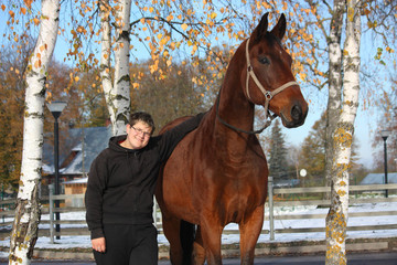 Teenager boy and brown horse portrait in autumn