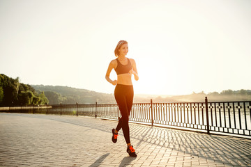 Running woman. Runner jogging in sunny bright light. Female fitn