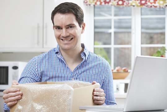 Happy Man Unpacking Online Purchase At Home