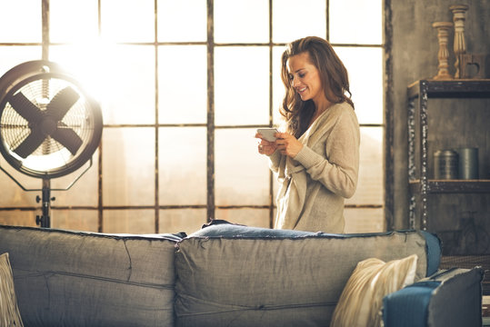 Young Woman Writing Sms In Loft Apartment