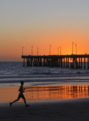 Obraz premium Silhouette of Jogger Running on beach at Sunset, California