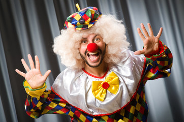 Funny clown in humorous concept against curtain