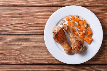 Roasted chicken legs with a garnish of pumpkin, top view