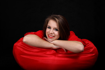 Uśmiechnięta dziewczyna na czerwonej poduszce.