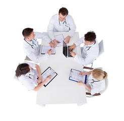 Fototapeta premium Doctors With Medical Charts And Laptop Discussing At Table