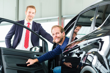 Verkäufer und Kunde mit Neuwagen von Autohaus