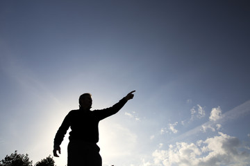 Fototapeta na wymiar Backlit of a man pointing towards the horizon
