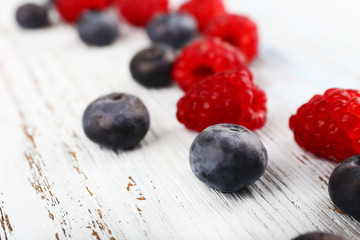 Raspberries and blueberries on wooden background closeup