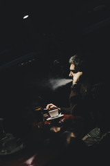 Fototapeta na wymiar Man drinking a coffee and smokes in cafe