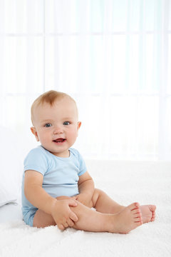 Cute baby boy on bed in room
