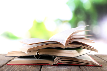 Three open books on wooden table on natural background