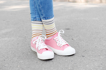 Female legs in colorful socks and sneakers outdoors