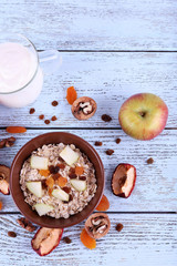 Fototapeta na wymiar Bowl of oatmeal, walnuts, dried apricots, apples and yogurt