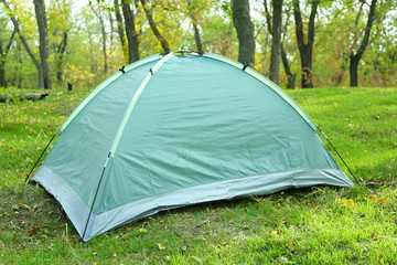 Touristic tent on green grass in a forest