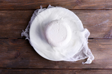 Cottage cheese on gauze on plate on wooden background