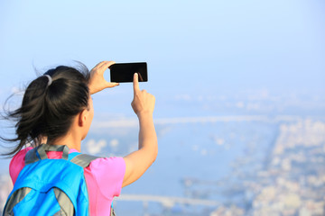 young woman hiker use smart phone taking photo at mountain peak 