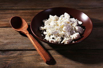 Cottage cheese on plate and spoon on wooden background