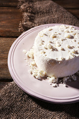 Cottage cheese on plate on sackcloth napkin on wooden