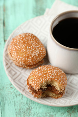 Cup of coffee with tasty cookie on color wooden background