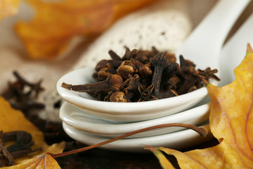 Carnation in spoon with yellow leaves on wooden background