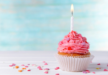 Delicious birthday cupcake on table on light blue background