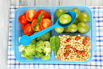 Tasty vegetarian food in plastic box on wooden table