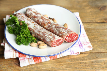 Italian salami on plate, on wooden background