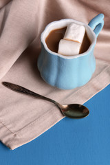 Cup of coffee with marshmallow and napkin on wooden table