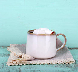 Cup of tasty hot cocoa, on wooden table, on color background