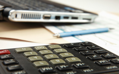 Calculator, pen, folder with documents, laptop