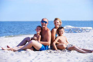 Smiling mother and father with children on the beach.