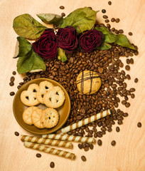dry red roses and cookies on coffee seeds