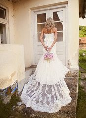 Fototapeta premium Blonde bride with veil by old house