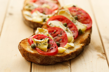 Bruschetta with tomatoes, brie cheese and capers