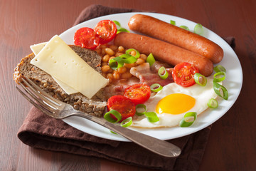 english breakfast with fried egg sausages bacon tomatoes beans