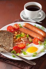 english breakfast with fried egg sausages bacon tomatoes beans