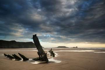 Landscape image of old shipwreck on beach at sunset in Summer