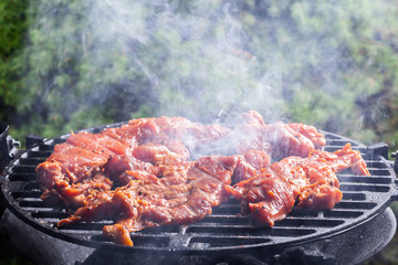 Grilling pork steaks on barbecue grill