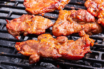 Grilling pork steaks on barbecue grill