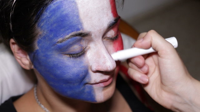 Closeup of a woman face painting flag of France.