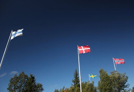 Flags of Finland, Denmark, Sweden and Norway blowing in the wind on dark blue sky