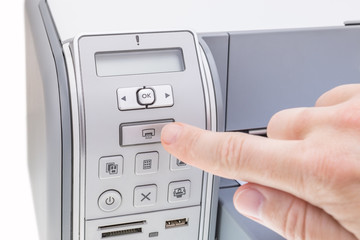 Office worker presses the button the printer. Close-up.