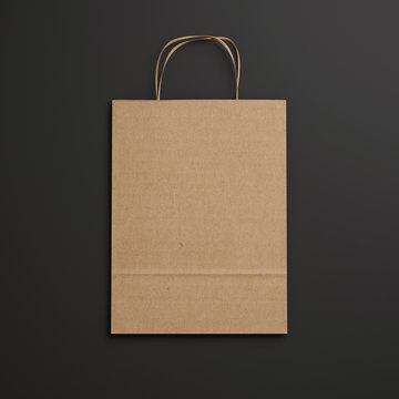 Brown paper bag with handles on black background