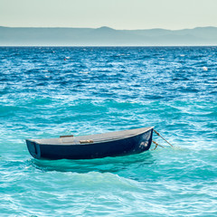 little blue boat is seesawing on waves in mediterrean