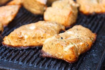 Salmon grilling on cast iron grill. Out of focus background.
