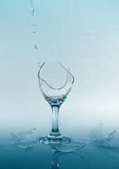 Clear water pour out of bottle splash into glass and spill with