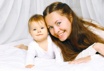 Portrait happy mother and cute baby on the bed home